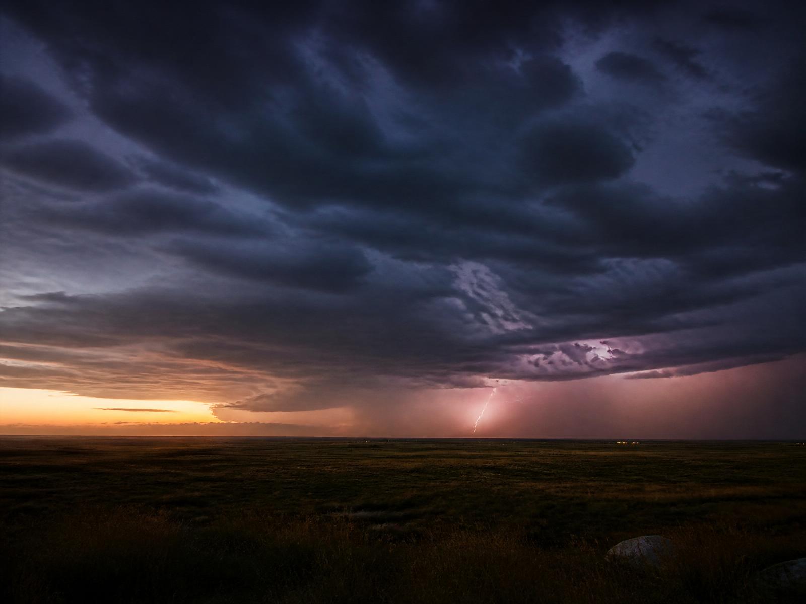 Distant thunderstorm rolling across a quiet plain at dusk